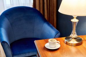 una taza de café en una mesa junto a una silla azul en Neo Classic by ACADEMIA en San Petersburgo
