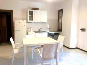 una cucina con tavolo e sedie bianchi di 3 bedrooms appartement with city view and furnished balcony at Suaredda traversa 3 km away from the beach a San Teodoro