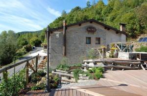 een stenen gebouw met een hek en een houten terras bij Agriturismo Spino Fiorito in Casola in Lunigiana