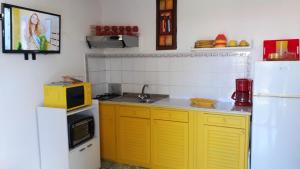 een keuken met gele kasten en een witte koelkast bij Appartement de 2 chambres avec vue sur la mer jardin clos et wifi a Le Vauclin in Le Vauclin
