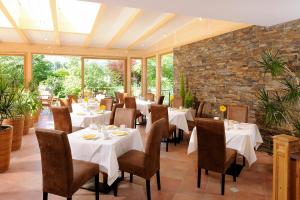 メラーノにあるホテル ガルニ パルタネスホフの白いテーブルと椅子、レンガの壁が特徴のレストラン