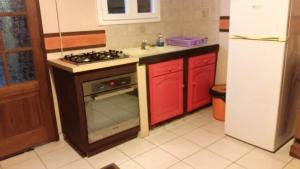 a kitchen with a stove and red cabinets and a refrigerator at Maison d'une chambre avec piscine privee jacuzzi et jardin clos a Le Moule in Le Moule