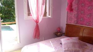 a bedroom with a bed and a window with pink curtains at Maison d'une chambre avec piscine privee jacuzzi et jardin clos a Le Moule in Le Moule