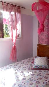 a bedroom with a bed with pink curtains and a window at Maison d'une chambre avec piscine privee jacuzzi et jardin clos a Le Moule in Le Moule