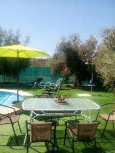 a table with chairs and an umbrella next to a pool at 4 bedrooms house with private pool enclosed garden and wifi at Montilla Cordoba in Jarata