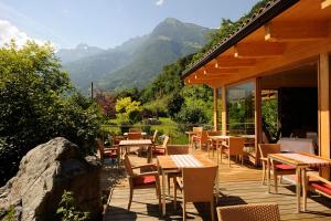 a wooden deck with tables and chairs and mountains at Hotel Garni Partaneshof in Merano