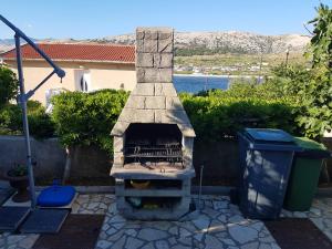 a stone fireplace in a yard with a trash can at 2 bedrooms appartement at Pag 100 m away from the beach with sea view enclosed garden and wifi in Pag