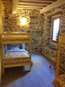 Cette chambre comprend 2 lits superposés et un mur en pierre. dans l'établissement Chalet de 4 chambres avec terrasse amenagee a Ascou a 3 km des pistes, à Ascou