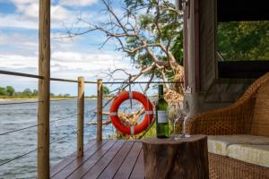 a bottle of wine and a glass on a porch at Ndhovu Safari Lodge in Mahango