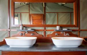 a bathroom with two sinks and a mirror at Ndhovu Safari Lodge in Mahango