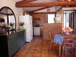 a kitchen with a table and a white refrigerator at Villa en pleine nature à Escource avec piscine privée in Escource