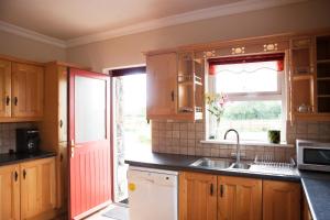 una cocina con armarios de madera y una puerta roja en Inviting 4-Bed House in Strokestown, en Grange