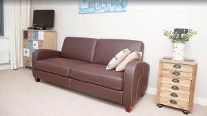 un sofá de cuero marrón en una sala de estar con mesa en Fabulous house very near Charlestown Harbour, en Charlestown