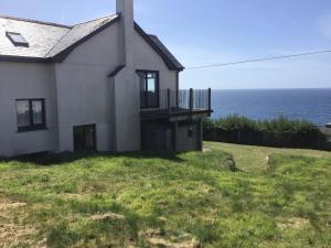 a house with a balcony and the ocean in the background at Captivating 8-Bed House in Porthleven in Porthleven