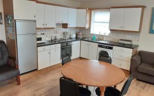 a kitchen with a wooden table and a kitchen with white cabinets at Cosy 2-Bed Cottage in Sligo in Enniscrone