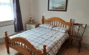 a bedroom with a wooden bed and a chair at Cosy 2-Bed Cottage in Sligo in Enniscrone
