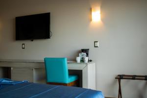 a room with a bed and a desk with a blue chair at Varali Grand Hotel in Mazatlán