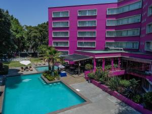 een hotel met een zwembad voor een roze gebouw bij Hotel Real de Puebla in Puebla