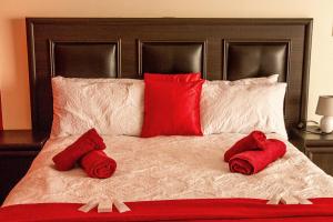 a bed with red pillows and red towels on it at Stay Cleverly Self Catering Apartments in Walvis Bay
