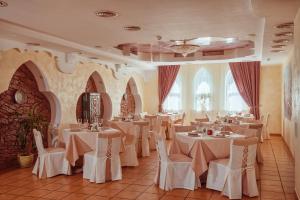 a restaurant with white tables and chairs in a room at Premier Hotel Shafran in Sumy