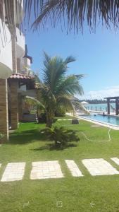 a house with a palm tree next to the water at WATER FRONT in Maceió