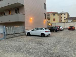 un coche blanco aparcado en un aparcamiento al lado de un edificio en la nostra casa... en Novara