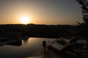 puesta de sol sobre una piscina con mesa y sillas en Villa Magnolia Corfu, en Perama