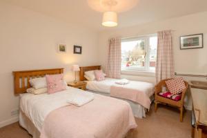 1 dormitorio con 2 camas y ventana en Beachview Holiday Flat 2 en Lossiemouth