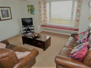 a living room with two leather couches and a coffee table at Beachview Holiday Flat 2 in Lossiemouth