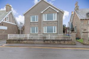 a house with a white fence in front of it at Beachview Holiday Flat 2 in Lossiemouth