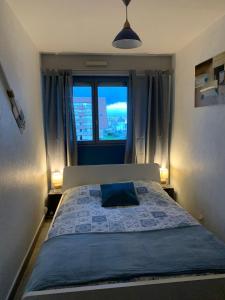 a bedroom with a bed with a blue pillow and a window at Villers Plage 1 in Villers-sur-Mer