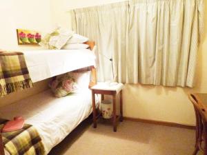 a bedroom with a bunk bed with a night stand and a table at Cosy 6 Person Cottage with Mountain View in Barrydale