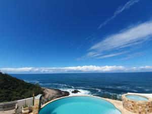 a swimming pool with a view of the ocean at Casa do Maracuja in Maricá