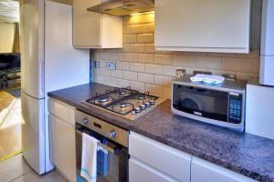 a kitchen with a stove and a microwave at Modern & Spacious - Walk to London ExCEL- Parking in London