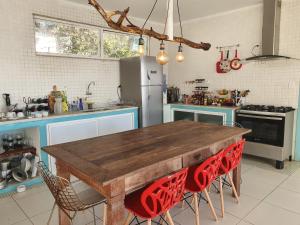 une cuisine avec une table en bois et des chaises rouges dans l'établissement Casa do Maracuja, à Maricá