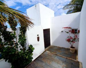 uma casa branca com uma porta e algumas plantas em Casa do Maracuja em Maricá