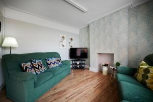 uma sala de estar com um sofá verde e uma televisão em Detached 3 Bed House Ideal for Long Stays & Pets em Mold