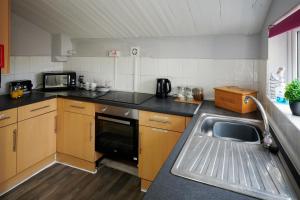 uma pequena cozinha com um lavatório e um micro-ondas em Detached 3 Bed House Ideal for Long Stays & Pets em Mold
