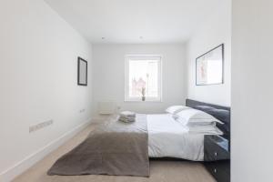 a white bedroom with a bed and a window at Luxury 2-Bed Flat parking and close to the tube in London
