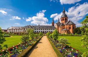 un jardin en face d'un grand bâtiment fleuri dans l'établissement Hotel MainChateau, à Seligenstadt