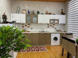 a kitchen with white cabinets and a washing machine at Gabala Sweet Home in Gabala