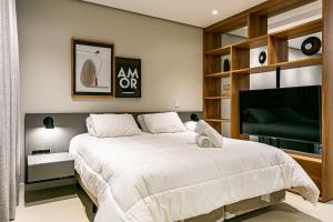 a bedroom with a large bed and a television at WI-FI 350MB | Foodhall | 450m do Shopping #CA14 in Florianópolis +39 photos