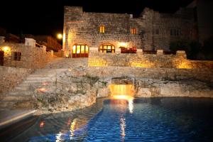 a stone building with a swimming pool at night at Villeleynah Holiday Home in Munxar