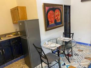 een keuken met een tafel en een tafel en een koelkast bij Chao Mamá Hostal in Santo Domingo