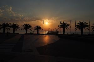 a sunset with palm trees in front of the ocean at Lilalo Ηotel in Paralia Katerinis