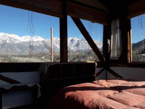 a bedroom with a view of snowy mountains from a window at Cabaña El Cóndor - Complejo El Taller in Potrerillos
