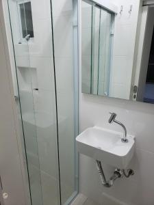 La salle de bains est pourvue d'un lavabo et d'une douche en verre. dans l'établissement APARTAMENTO COM VISTA PARA O MAR NA Av ATLANTICA EM BALNEARIO CAMBORIU, à Balneário Camboriú