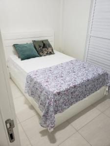 Dormitorio blanco con cama con manta de flores en APARTAMENTO COM VISTA PARA O MAR NA Av ATLANTICA EM BALNEARIO CAMBORIU, en Balneário Camboriú