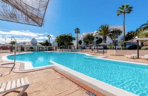 una gran piscina con sillas y palmeras en Apartamento Giovanni 09 Playa Roca, en Costa Teguise