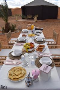 a white table with food on it in the desert at Tuda Luxury Camp in Merzouga